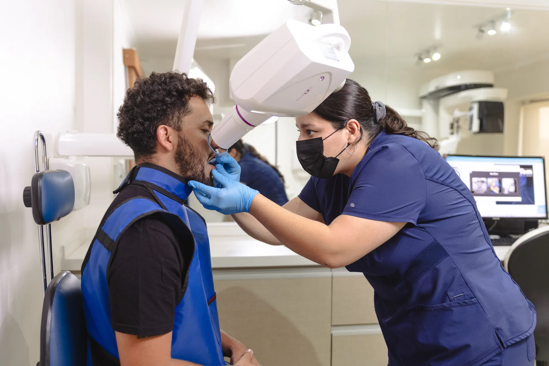 Profesional de i-maxval tomando una radiografía intraoral periapical a un paciente con delantal plomado en Valdivia